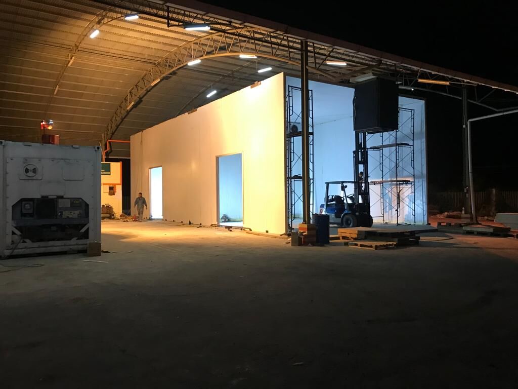 Large insulated cold room being built inside a warehouse at night